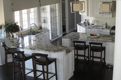 Idéer för ett mellanstort modernt kök, med en undermonterad diskho, luckor med upphöjd panel, vita skåp, marmorbänkskiva, vitt stänkskydd, stänkskydd i keramik, rostfria vitvaror, mörkt trägolv, en köksö och brunt golv