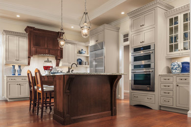 Inspiration for a large timeless u-shaped dark wood floor enclosed kitchen remodel in Other with an undermount sink, shaker cabinets, beige cabinets, granite countertops, white backsplash, stone tile backsplash, stainless steel appliances and an island