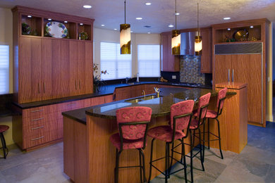 Example of a large trendy u-shaped ceramic tile kitchen design in Sacramento with an undermount sink, flat-panel cabinets, medium tone wood cabinets, granite countertops, green backsplash, glass tile backsplash, stainless steel appliances and an island