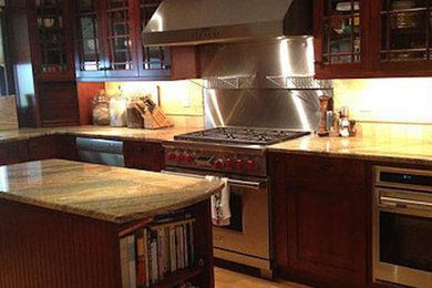 Example of an u-shaped light wood floor kitchen design in Philadelphia with glass-front cabinets, medium tone wood cabinets, granite countertops, ceramic backsplash, stainless steel appliances and an island