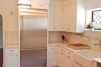 Mid-sized elegant medium tone wood floor enclosed kitchen photo in New York with a farmhouse sink, beaded inset cabinets, white cabinets, marble countertops, white backsplash, stainless steel appliances and no island