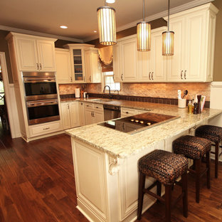 Mid-sized traditional open concept kitchen inspiration - Example of a mid-sized classic u-shaped light wood floor open concept kitchen design in Atlanta with a double-bowl sink, raised-panel cabinets, white cabinets, granite countertops, beige backsplash, stone tile backsplash, stainless steel appliances and a peninsula