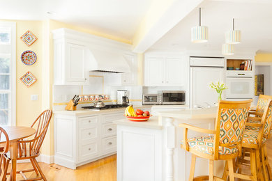 На фото: большая угловая кухня в классическом стиле с обеденным столом, фасадами с утопленной филенкой, белыми фасадами и островом с