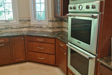ワシントンD.C.にあるおしゃれなキッチン (中間色木目調キャビネット、御影石カウンター、マルチカラーのキッチンパネル、シルバーの調理設備) の写真