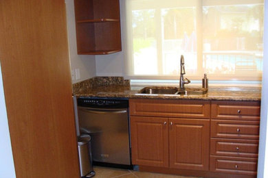 マイアミにある中くらいなおしゃれなキッチン (ダブルシンク、中間色木目調キャビネット、御影石カウンター、シルバーの調理設備) の写真