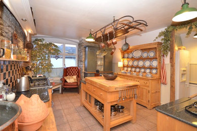 デヴォンにある中くらいなシャビーシック調のおしゃれなキッチン (中間色木目調キャビネット、木材カウンター) の写真
