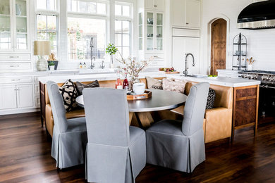 Example of a large transitional l-shaped dark wood floor eat-in kitchen design in Salt Lake City with a farmhouse sink, recessed-panel cabinets, white cabinets, marble countertops, white backsplash, ceramic backsplash, paneled appliances and an island