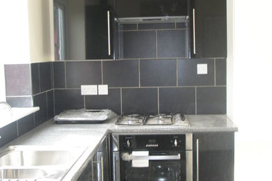 Mittelgroße Moderne Küche ohne Insel mit Doppelwaschbecken, schwarzen Schränken und schwarzen Elektrogeräten in Manchester