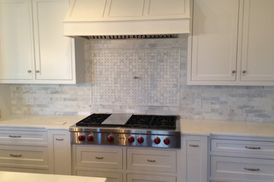 Example of a classic eat-in kitchen design in Boston with white backsplash, stainless steel appliances, recessed-panel cabinets, white cabinets, quartzite countertops and an island