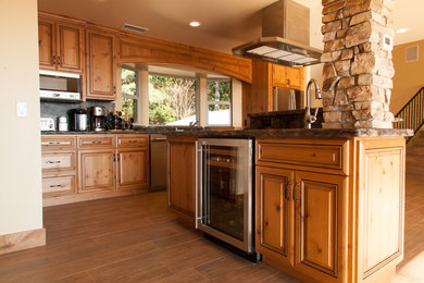 Example of a large mountain style l-shaped medium tone wood floor open concept kitchen design in Sacramento with a double-bowl sink, raised-panel cabinets, medium tone wood cabinets, granite countertops, metallic backsplash, stone slab backsplash, stainless steel appliances and an island