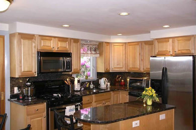 Example of a kitchen design in Providence with light wood cabinets and an island