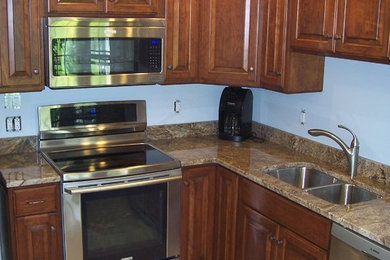 Example of a large l-shaped kitchen design in New York with a double-bowl sink, raised-panel cabinets, medium tone wood cabinets, granite countertops and stainless steel appliances