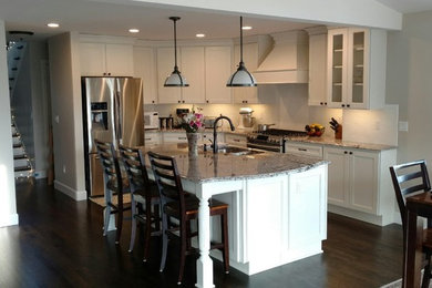 Inspiration for a mid-sized timeless l-shaped dark wood floor and brown floor open concept kitchen remodel in Detroit with a double-bowl sink, shaker cabinets, white cabinets, granite countertops, white backsplash, subway tile backsplash, stainless steel appliances and an island