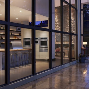 Ispirazione per una grande cucina ad ambiente unico design con ante lisce, top alla veneziana, elettrodomestici in acciaio inossidabile, pavimento in cemento e isola