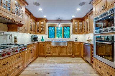 Inredning av ett klassiskt avskilt, mellanstort u-kök, med en rustik diskho, luckor med infälld panel, skåp i mellenmörkt trä, granitbänkskiva, beige stänkskydd, stänkskydd i stenkakel, rostfria vitvaror, mellanmörkt trägolv och brunt golv