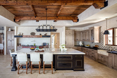 Huge tuscan l-shaped travertine floor and beige floor kitchen photo in Los Angeles with a farmhouse sink, quartzite countertops, multicolored backsplash, ceramic backsplash, an island, raised-panel cabinets, medium tone wood cabinets and black countertops