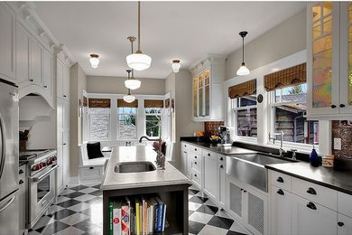 Example of a large trendy galley porcelain tile and multicolored floor eat-in kitchen design in Phoenix with a farmhouse sink, shaker cabinets, white cabinets, solid surface countertops, metallic backsplash, ceramic backsplash, stainless steel appliances and an island
