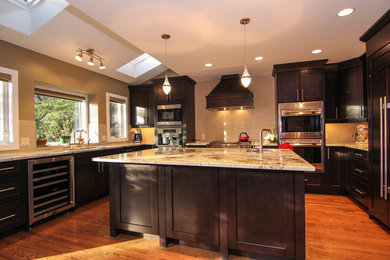 Large transitional u-shaped dark wood floor and brown floor eat-in kitchen photo in Calgary with an undermount sink, recessed-panel cabinets, black cabinets, granite countertops, beige backsplash, matchstick tile backsplash, stainless steel appliances, an island and beige countertops