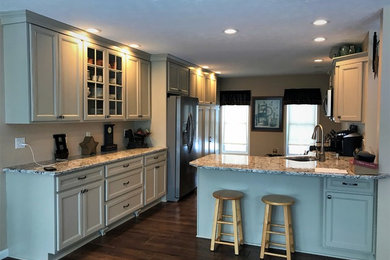 Large elegant galley dark wood floor and brown floor enclosed kitchen photo in New York with an undermount sink, recessed-panel cabinets, gray cabinets, granite countertops, stainless steel appliances, a peninsula and gray countertops