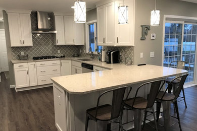 Large trendy u-shaped dark wood floor and brown floor eat-in kitchen photo in New York with an undermount sink, shaker cabinets, white cabinets, quartzite countertops, gray backsplash, ceramic backsplash, stainless steel appliances, a peninsula and beige countertops