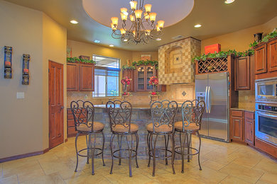 Mid-sized mountain style u-shaped limestone floor kitchen photo in Albuquerque with an undermount sink, raised-panel cabinets, medium tone wood cabinets, granite countertops, beige backsplash, stone tile backsplash, stainless steel appliances and an island