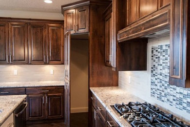 Example of a mid-sized l-shaped dark wood floor kitchen pantry design in Las Vegas with granite countertops, an island, dark wood cabinets, white backsplash and stainless steel appliances