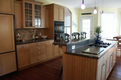 Mid-sized arts and crafts galley laminate floor and brown floor eat-in kitchen photo in New York with shaker cabinets, light wood cabinets, beige backsplash, stone tile backsplash, paneled appliances, an island and a double-bowl sink