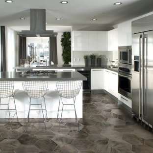 Immagine di una grande cucina design con ante lisce, ante bianche, top in granito, paraspruzzi bianco, elettrodomestici in acciaio inossidabile, pavimento in linoleum e penisola
