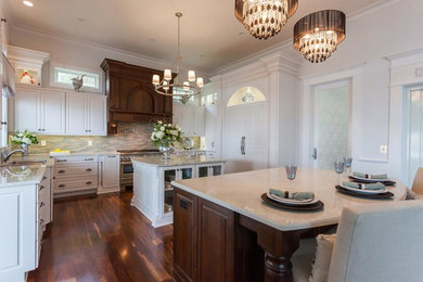 Kitchen - large traditional u-shaped dark wood floor and brown floor kitchen idea in Charleston with an undermount sink, raised-panel cabinets, white cabinets, quartzite countertops, multicolored backsplash, glass tile backsplash, paneled appliances and two islands