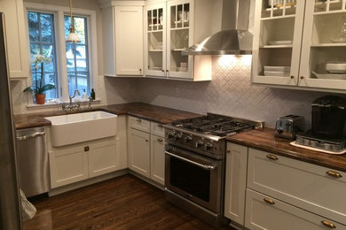 ミネアポリスにある広いコンテンポラリースタイルのおしゃれなキッチン (エプロンフロントシンク、オープンシェルフ、白いキャビネット、木材カウンター、白いキッチンパネル、セラミックタイルのキッチンパネル、シルバーの調理設備、無垢フローリング、茶色い床) の写真