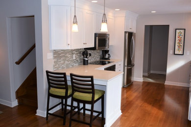 Eat-in kitchen - small transitional galley dark wood floor eat-in kitchen idea in Indianapolis with an undermount sink, flat-panel cabinets, white cabinets, solid surface countertops, gray backsplash, glass tile backsplash, stainless steel appliances and an island