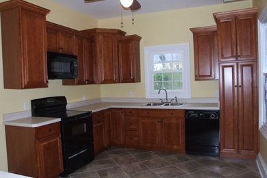 Example of a l-shaped kitchen design in Richmond with a double-bowl sink, beaded inset cabinets, medium tone wood cabinets and black appliances