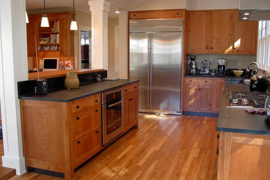 Eat-in kitchen - mid-sized craftsman l-shaped medium tone wood floor eat-in kitchen idea in Boston with an undermount sink, shaker cabinets, medium tone wood cabinets, granite countertops, stone slab backsplash, stainless steel appliances and an island
