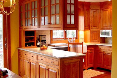 Mid-sized arts and crafts u-shaped medium tone wood floor eat-in kitchen photo in New York with a farmhouse sink, raised-panel cabinets, medium tone wood cabinets, granite countertops, beige backsplash, stone tile backsplash, stainless steel appliances and an island