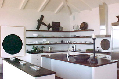 ロサンゼルスにあるコンテンポラリースタイルのおしゃれなキッチン (アンダーカウンターシンク、フラットパネル扉のキャビネット、白いキャビネット、御影石カウンター、白いキッチンパネル、シルバーの調理設備) の写真