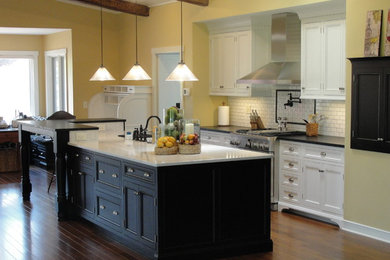Example of a large classic galley dark wood floor eat-in kitchen design in Other with shaker cabinets, white cabinets, quartzite countertops, white backsplash, subway tile backsplash, an island, a farmhouse sink and stainless steel appliances