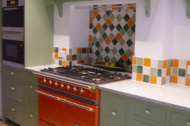 ロンドンにある高級な広いトラディショナルスタイルのおしゃれなキッチン (一体型シンク、シェーカースタイル扉のキャビネット、緑のキャビネット、御影石カウンター、マルチカラーのキッチンパネル、セラミックタイルのキッチンパネル、パネルと同色の調理設備) の写真