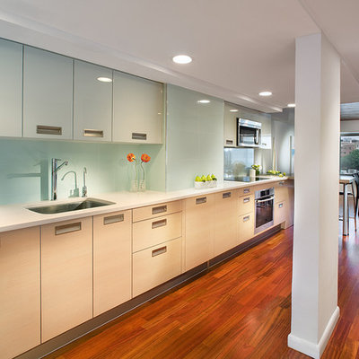 Example of a large trendy single-wall medium tone wood floor and brown floor eat-in kitchen design in New York with flat-panel cabinets, a single-bowl sink, stainless steel appliances, blue backsplash, light wood cabinets, glass tile backsplash and no island