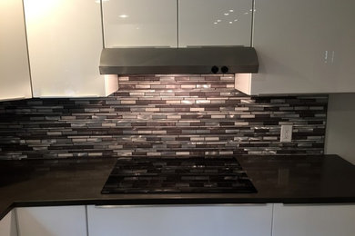 Example of a trendy kitchen design in Portland Maine with flat-panel cabinets, white cabinets, quartz countertops, multicolored backsplash and matchstick tile backsplash