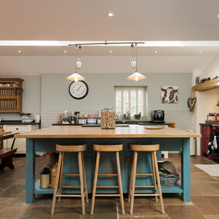 Esempio di una cucina country con ante in stile shaker, ante rosse, paraspruzzi rosso, paraspruzzi in mattoni, elettrodomestici neri, pavimento marrone e top nero