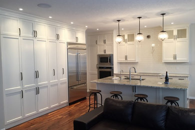Inspiration for a contemporary galley light wood floor open concept kitchen remodel in Calgary with an undermount sink, shaker cabinets, white cabinets, wood countertops, stainless steel appliances, an island, white backsplash and subway tile backsplash