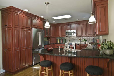 Kitchen - medium tone wood floor kitchen idea in Charlotte with dark wood cabinets, granite countertops and metallic backsplash