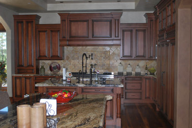 Example of a dark wood floor kitchen design in Denver with a drop-in sink, raised-panel cabinets, dark wood cabinets, granite countertops, beige backsplash, ceramic backsplash, paneled appliances and an island