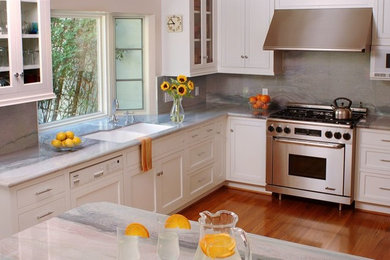 Example of a trendy u-shaped medium tone wood floor eat-in kitchen design in Santa Barbara with a double-bowl sink, recessed-panel cabinets, white cabinets, stainless steel appliances and an island