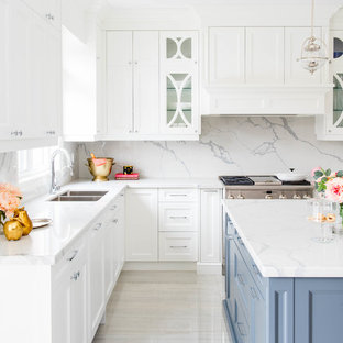 Photo of a mid-sized transitional l-shaped open plan kitchen in San Diego with a double-bowl sink, shaker cabinets, white cabinets, white splashback, stone slab splashback, stainless steel appliances, marble floors, with island, marble benchtops and white floor.