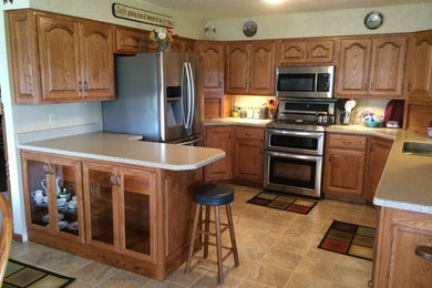Example of a mid-sized classic u-shaped ceramic tile and beige floor kitchen design in Other with an undermount sink, raised-panel cabinets, medium tone wood cabinets, laminate countertops, stainless steel appliances and a peninsula