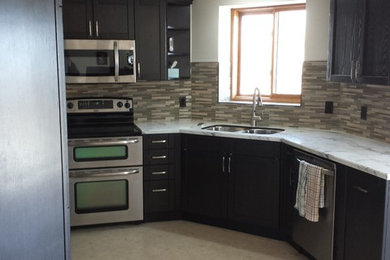 Example of a mid-sized transitional u-shaped ceramic tile and beige floor enclosed kitchen design in Calgary with an undermount sink, shaker cabinets, stainless steel appliances, black cabinets, marble countertops, beige backsplash, matchstick tile backsplash and no island