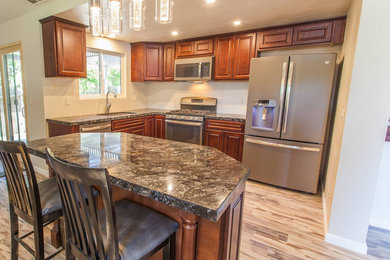 Example of a mid-sized l-shaped light wood floor kitchen design in Sacramento with medium tone wood cabinets, granite countertops, stainless steel appliances and an island