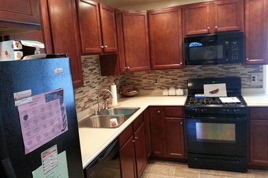 Example of a mid-sized l-shaped linoleum floor open concept kitchen design in Other with a double-bowl sink, medium tone wood cabinets, solid surface countertops, matchstick tile backsplash and black appliances