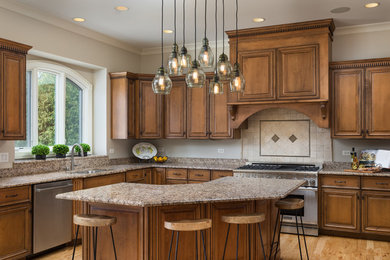 Example of a large classic l-shaped medium tone wood floor open concept kitchen design in Chicago with an undermount sink, raised-panel cabinets, dark wood cabinets, granite countertops, beige backsplash, ceramic backsplash, stainless steel appliances and an island